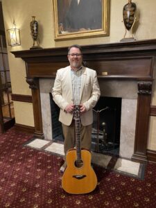 Jeremiah Williams standing with his acoustic guitar at York Country Club