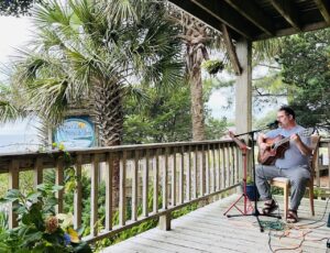 Jeremiah Williams playing acoustic guitar on a porch in Ocracoke