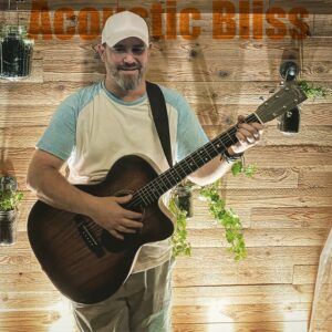 Jeremiah Williams holding an acoustic guitar against a wooden wall