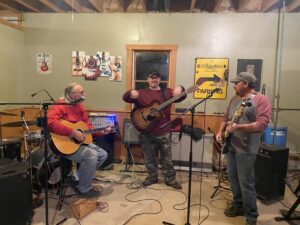 Three musicians playing acoustic and electric guitars together