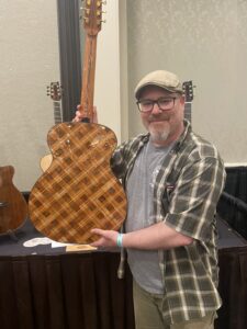 Jeremiah Williams displaying the patterned wooden back of an acoustic guitar